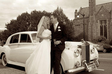 couple toasting by antique Rolls Royce