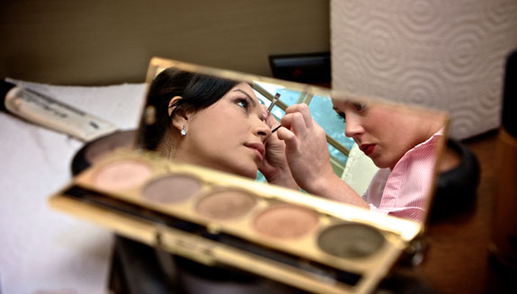 bride's makeup stylist in cosmetic mirror